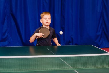 bir tenis t-shirt oyun Masa Tenisi mavi bir arka plan üzerinde içinde bir oğlan