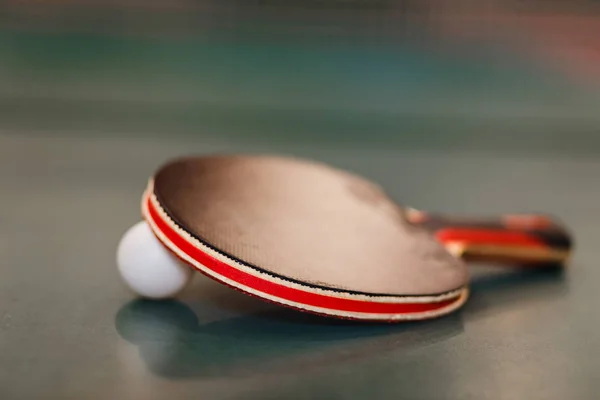 black table tennis racket and tennis ball on the table tennis table