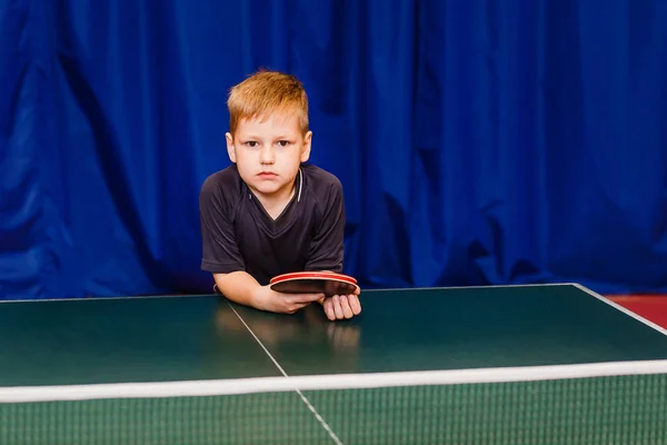 serious boy at the table tennis table looking at the camera