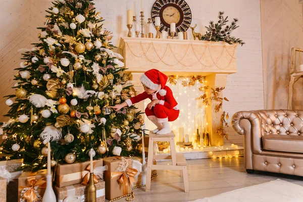 küçük çocuk Noel Baba'nın kırmızı takım elbise için bir Noel ağacı süsle