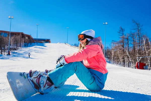 Genç bir snowboard bir dağ yamacında kışın oturur.