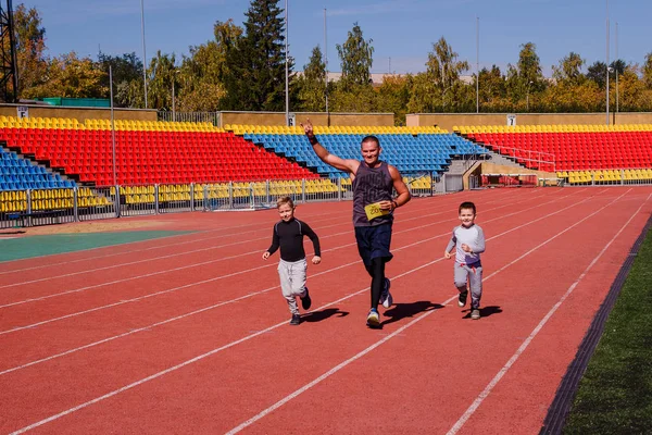 a man with two children running for sports stadium