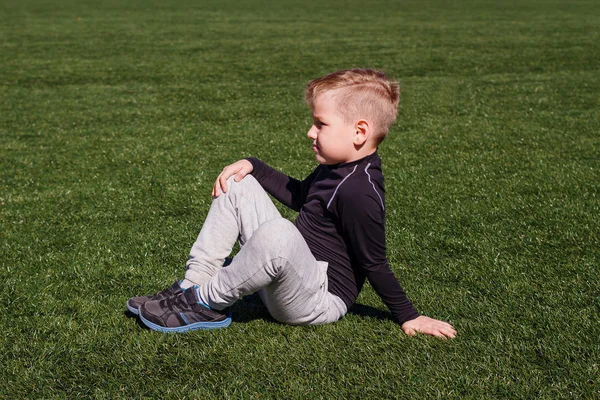 Мальчик Спортивной Одежде Сидит Зеленой Траве Открытом Воздухе — стоковое фото