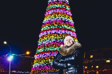 Noel ağacı yakınındaki kürklü deri ceketli adamı