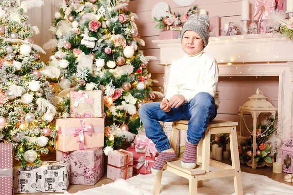 cute boy in knitted hat and sweater Christmas Interior. smiling boy in knitted socks sitting under the Christmas tree