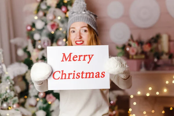Merry Christmas sign on white background in the hands of women