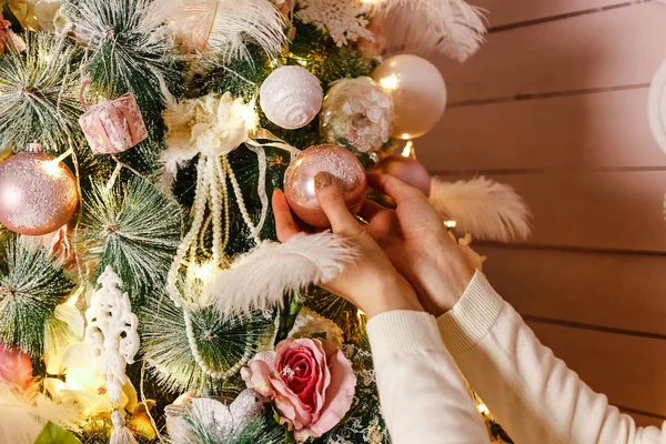 women\'s hands hang ball on Christmas tree, decorating the Christmas tree