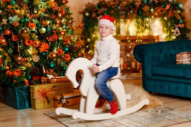 bir oyuncak ahşap sallanan bir şekilde dekore edilmiş Noel odada Binicilik şirin mutlu bebek.