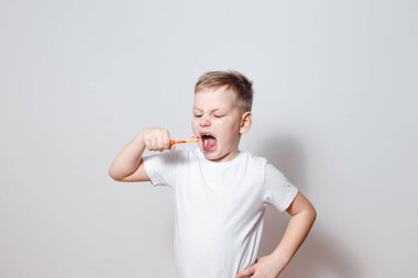 Altı yıl eski fırçalama diş geniş açık ağzını beyaz arka plan üzerinde beyaz t-shirt