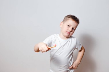 beyaz bir t-shirt bir çocuk beyaz bir arka plan üzerinde dişlerini fırçalamayı istemiyor