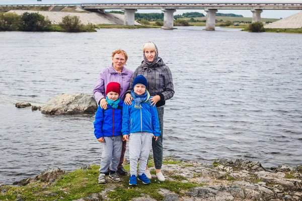 two elderly woman with malenkmi children on the banks of the river. river bridge