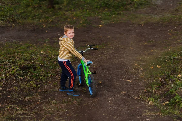 smiling boy wheels bike path. seven-year-old boy rolls a bike