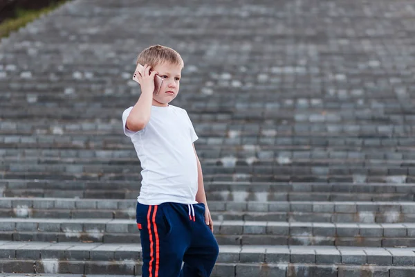 Серьезный Мальчик Стоящий Ступеньках Разговаривающий Телефону Улице Мальчик Спортивной Одежде — стоковое фото