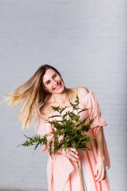 beyaz zemin üzerine gülen genç otuz yaşında bir kadın. Kadın ve bahar. Fern şube onun elinde