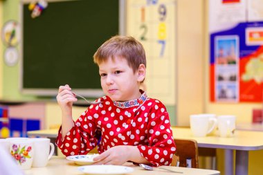 altı yaşındaki Rus çocuk yulaf lapası anaokulunda yiyor.