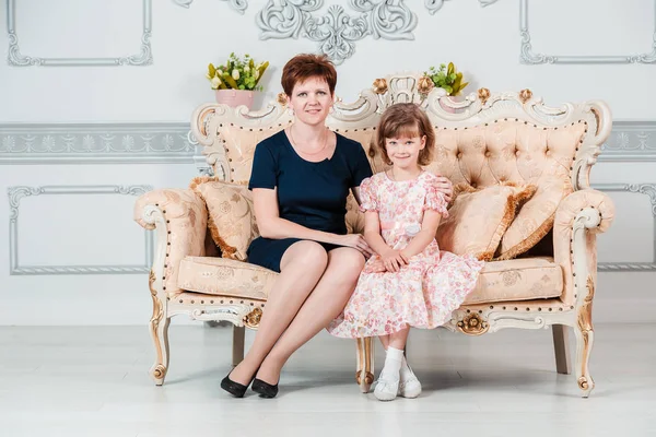 一个年轻的母亲和六岁的女儿坐在沙发上 — 图库照片