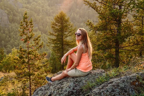 Блондинка красивая женщина туристка в солнечных очках, сидящая на краю — стоковое фото