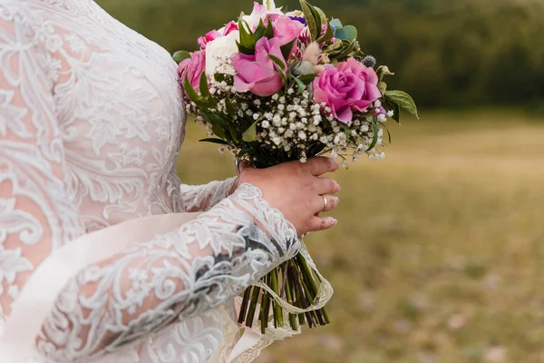 Delicate bouquet of roses in the hands of the bride on a blurred background — Stock Photo, Image