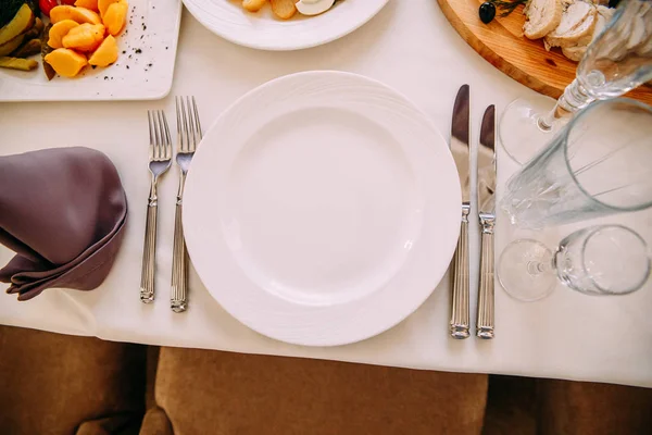 Assiette blanche plate, couteaux et fourchettes sur la table dans le restaurant — Photo