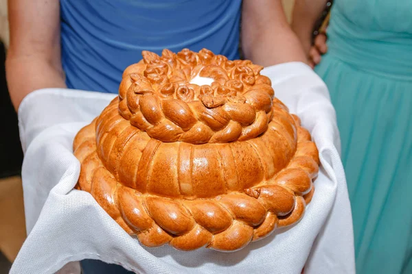 A woman holds a large beautiful Golden loaf on a towel. Bread — Stock Photo, Image