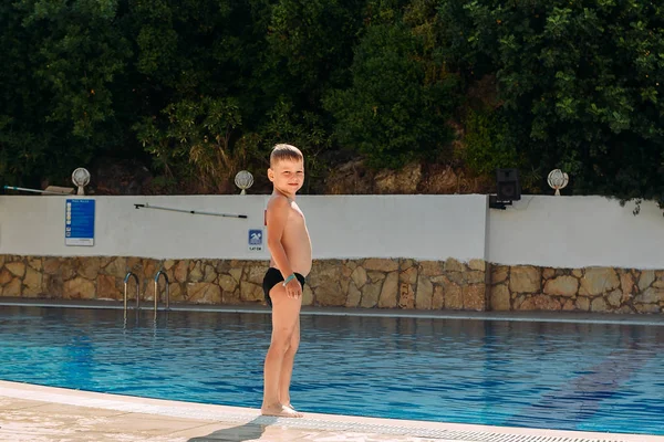 De lachende jongen in boomstammen zwemwater op vakantie — Stockfoto