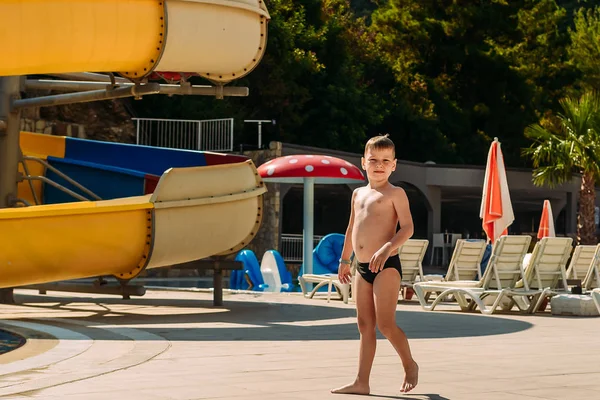 Хорошо накормленный шестилетний мальчик в плавках гуляет по территории отеля в Турции. Солнечное лето — стоковое фото