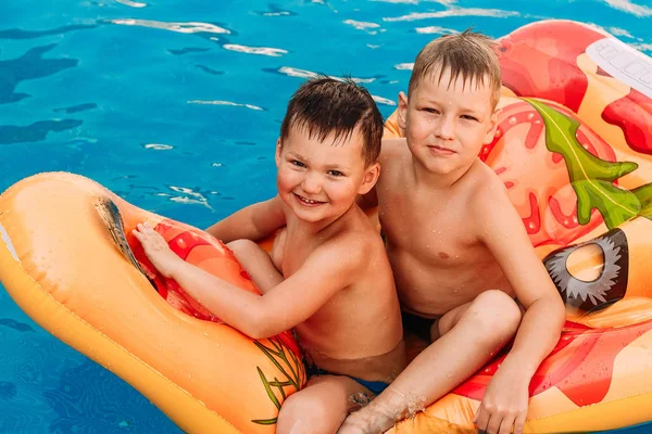 Δύο αγόρια μαυρισμένο ευτυχισμένη preschooler κάθονται σε ένα στρώμα αέρα στην πισίνα. καυτό καλοκαίρι — Φωτογραφία Αρχείου