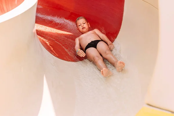 Šest rok starý chlapec v plavkách se vodní skluzavku v — Stock fotografie