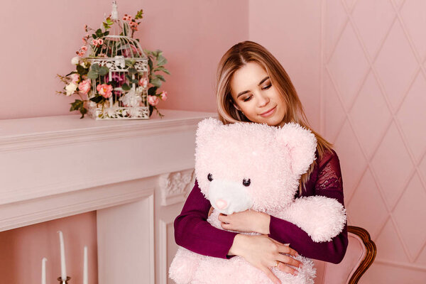 Молодая женщина нежно обнимает плюшевого мишку
