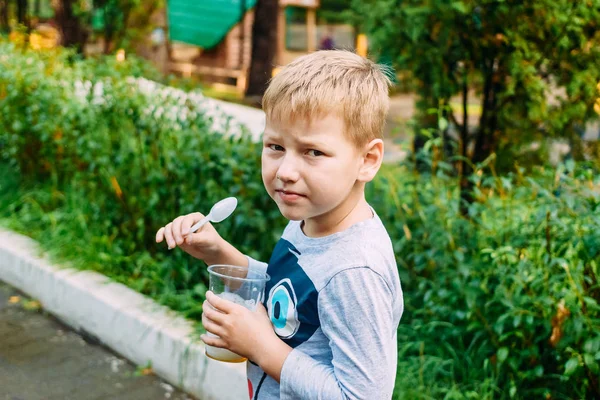 Шестилетний мальчик ест пластиковую ложку полезного кислородного коктейля — стоковое фото