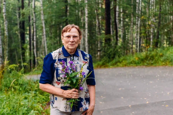 Женщина пенсионерка с букетом полевых цветов — стоковое фото