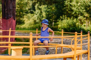 beş yaşındaki gülümseyen Kafkas çocuk Park büyük bir çocuk Carousel sürme bir şapka