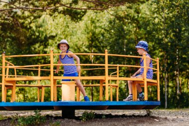 şapka ve t-shirt küçük çocuklar Park büyük bir demir Carousel binmek