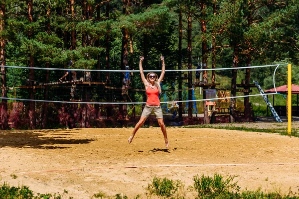 Молодая женщина прыгает на волейбольное поле на пляже — стоковое фото