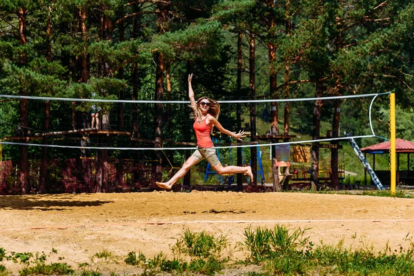 Una giovane donna salta alta in estate sulla sabbia — Foto Stock