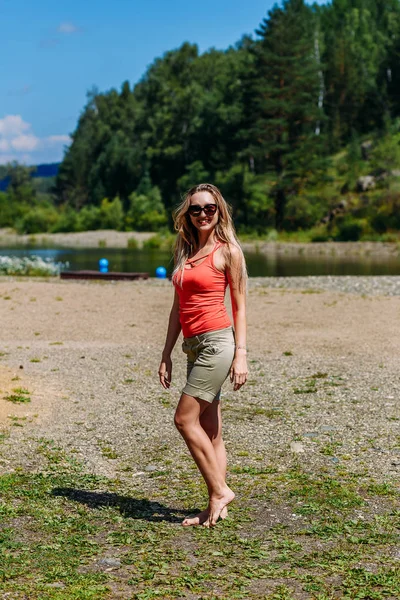 Sportig leende kvinna i sol glasögon står på stranden på sommaren — Stockfoto