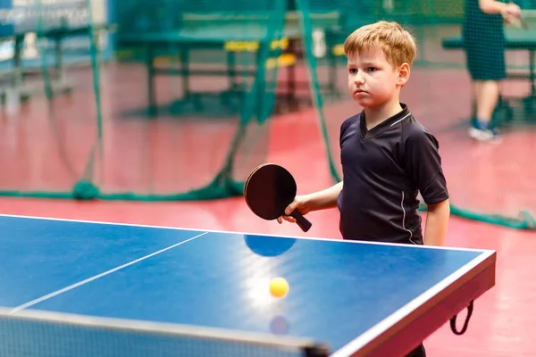 Кавказский мальчик играет в настольный теннис за синим столом — стоковое фото