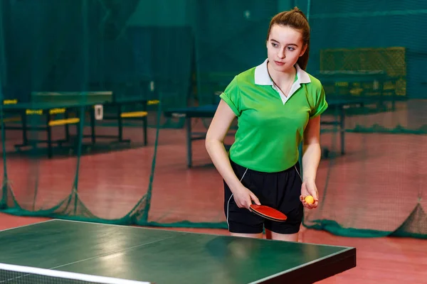 Krásná teenagerka ve sportovním formátu servíruje v tělocvičně stolní tenis. ping pong — Stock fotografie