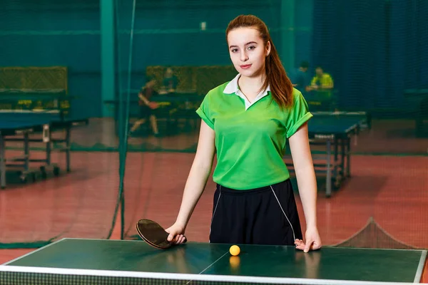 Atraktivní Kavkazská dívka se tyčí u stolního tenisu a dívá se na kameru. Mladý sportovní spolk — Stock fotografie