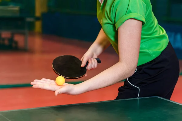 black table tennis racket and ball in women's hands