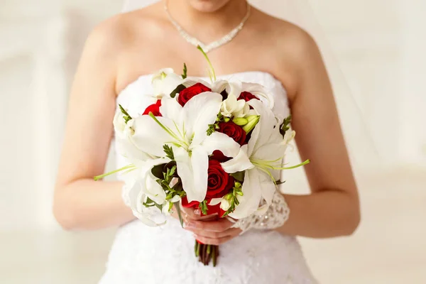 Невеста с букетом белых лилий и красных роз — стоковое фото