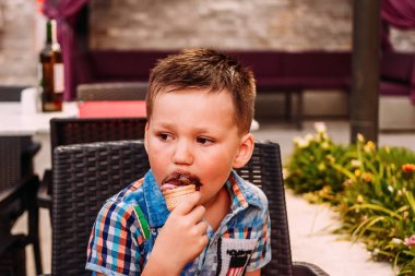 Beş yaşındaki bir çocuk yazın waffle konisinde çikolatalı dondurma yer. .