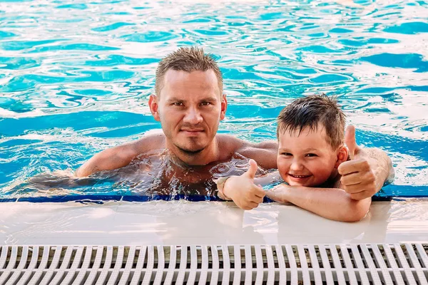Χαρούμενος χαμογελαστός πατέρας και το παιδί σε εξωτερική πισίνα με μπλε νερό. — Φωτογραφία Αρχείου