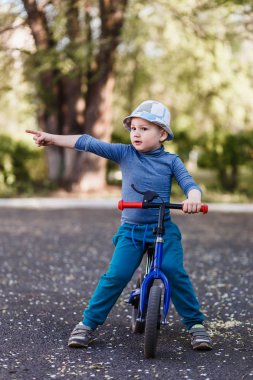 şapkalı dört yaşındaki gülümseyen bir çocuk sağ elini bir jest yapar