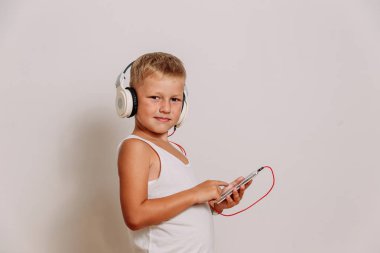 beyaz arka planda büyük beyaz kulaklıklar içinde gülümseyen çocuk