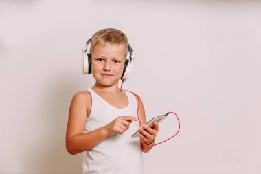 beyaz arka planda büyük beyaz kulaklıklar içinde gülümseyen çocuk