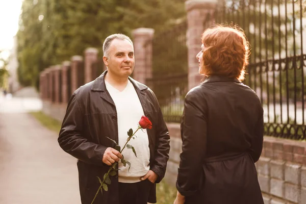 Elli adam bir kadına kırmızı bir gül verir. Yaz gün batımında orta yaşlı karı koca — Stok fotoğraf