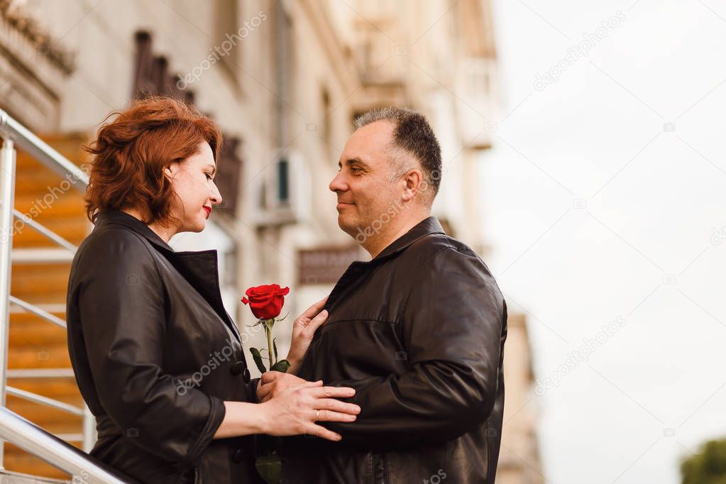 happy middle-aged man and woman holding red rose. Love in town. Appointment
