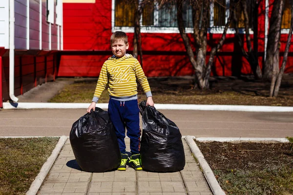 Il bambino tiene sacchi pieni della spazzatura — Foto Stock