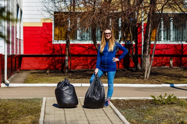 O femeie de 30 de ani şi pungi de gunoi din plastic în aer liber. Probleme de mediu — Fotografie, imagine de stoc